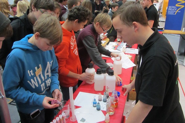 Azubi Tobias Handwerker erklärt Schülern auf der Infomesse den Chemikanten-Beruf (Foto: Zschimmer & Schwarz).